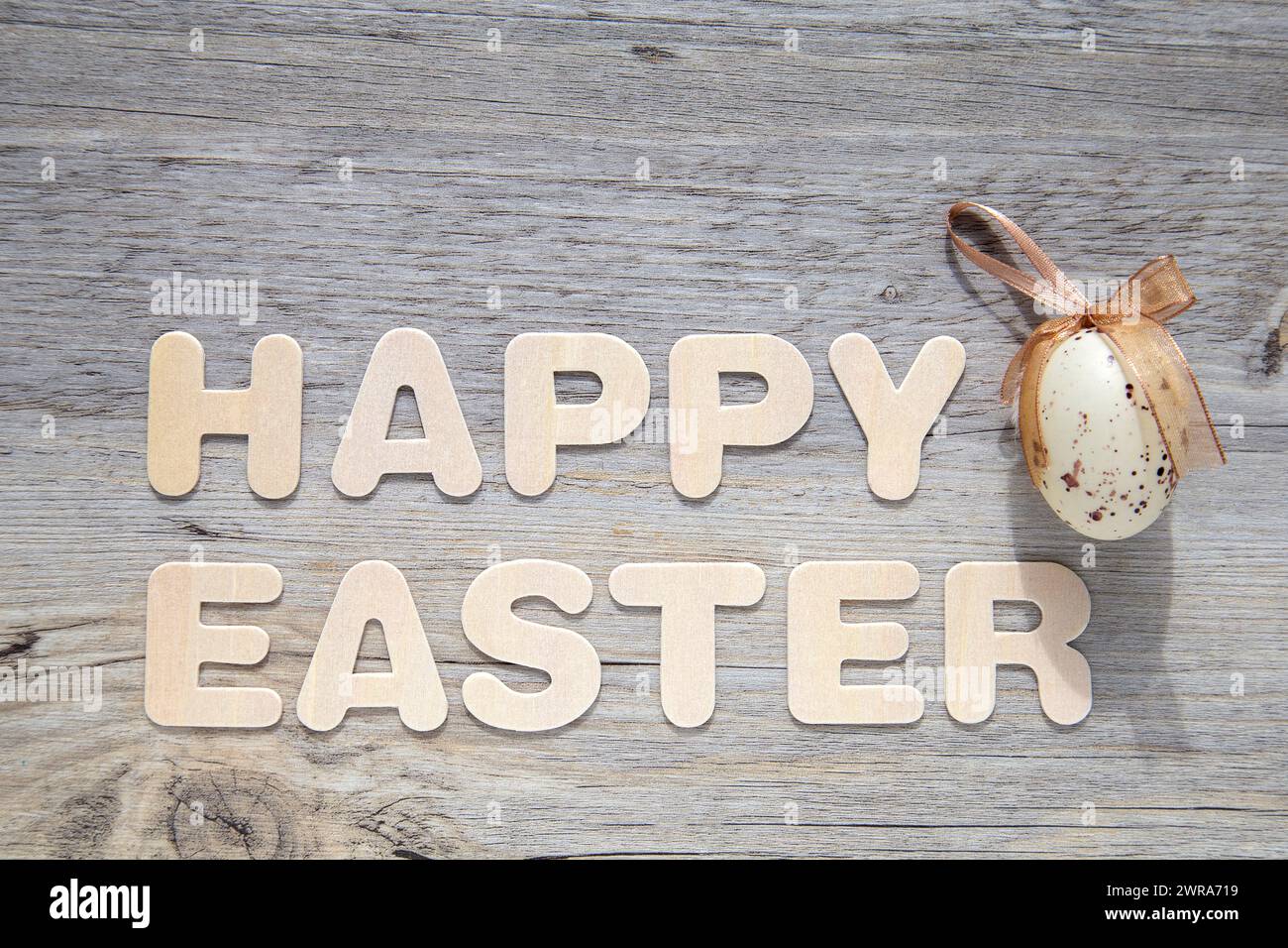 Dekoratives Osterei auf hölzernem Hintergrund mit dem Text „Happy Easter“. Stockfoto
