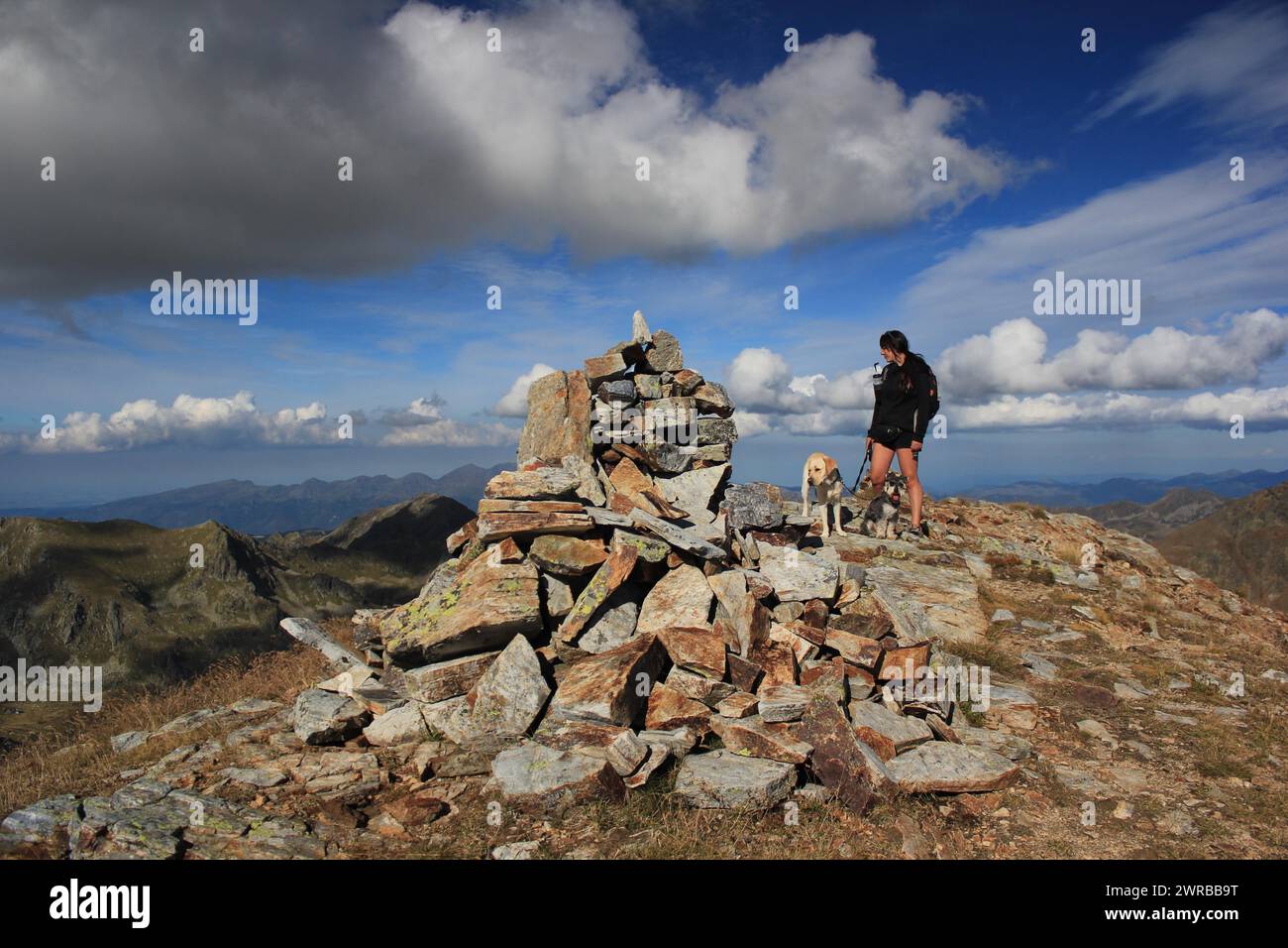 Person mit Hund Wandern auf einem Bergweg mit Steinen, erstaunliche Hunde in der Natur Stockfoto