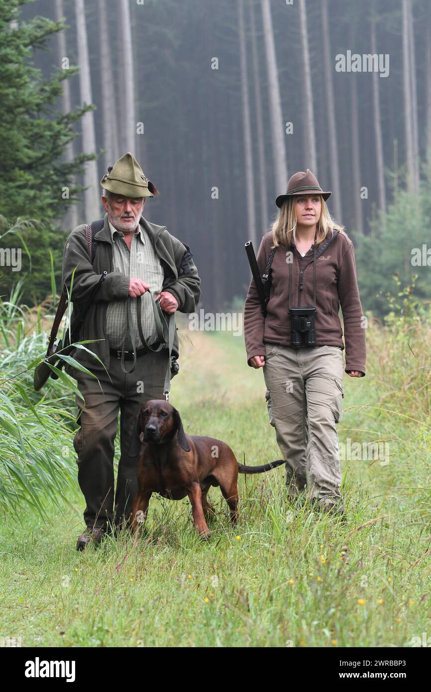 Jäger und Jägerin, begleitet von Jagdhund Bayerischer Gebirgshund, Allgaeu, Bayern, Deutschland Stockfoto