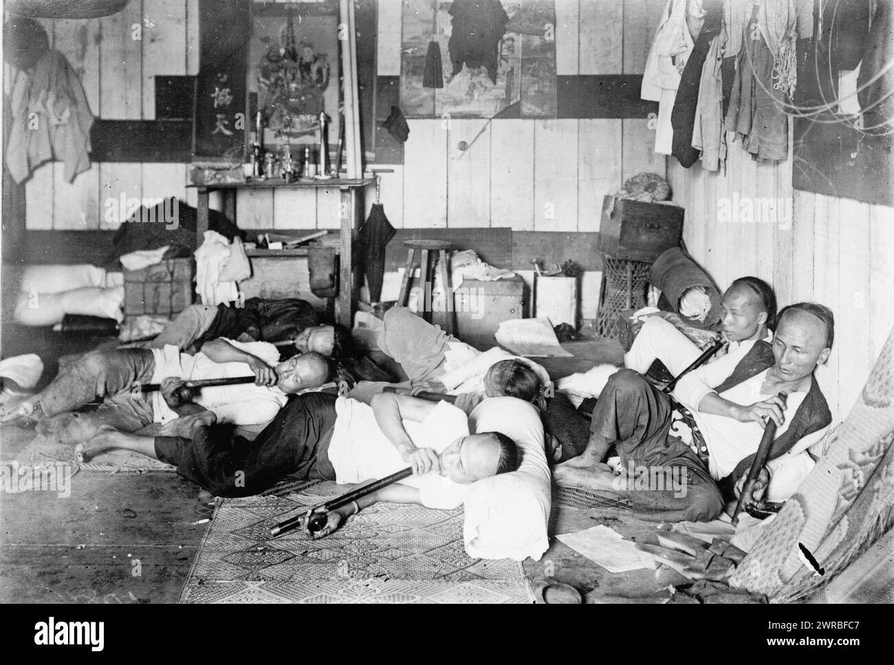 Opiumden auf der Malinta Street, Manila, Philippinen, Foto zeigt eine Innenansicht einer Opiumhöhle mit mehreren Männern, die sich zurücklehnen und lange Opiumpfeifen rauchen., 1924, Opiumhöhlen, Philippinen, Manila, 1920-1930, Fotodrucke, 1920-1930., Fotodrucke, 1920-1930, 1 Fotodruck Stockfoto