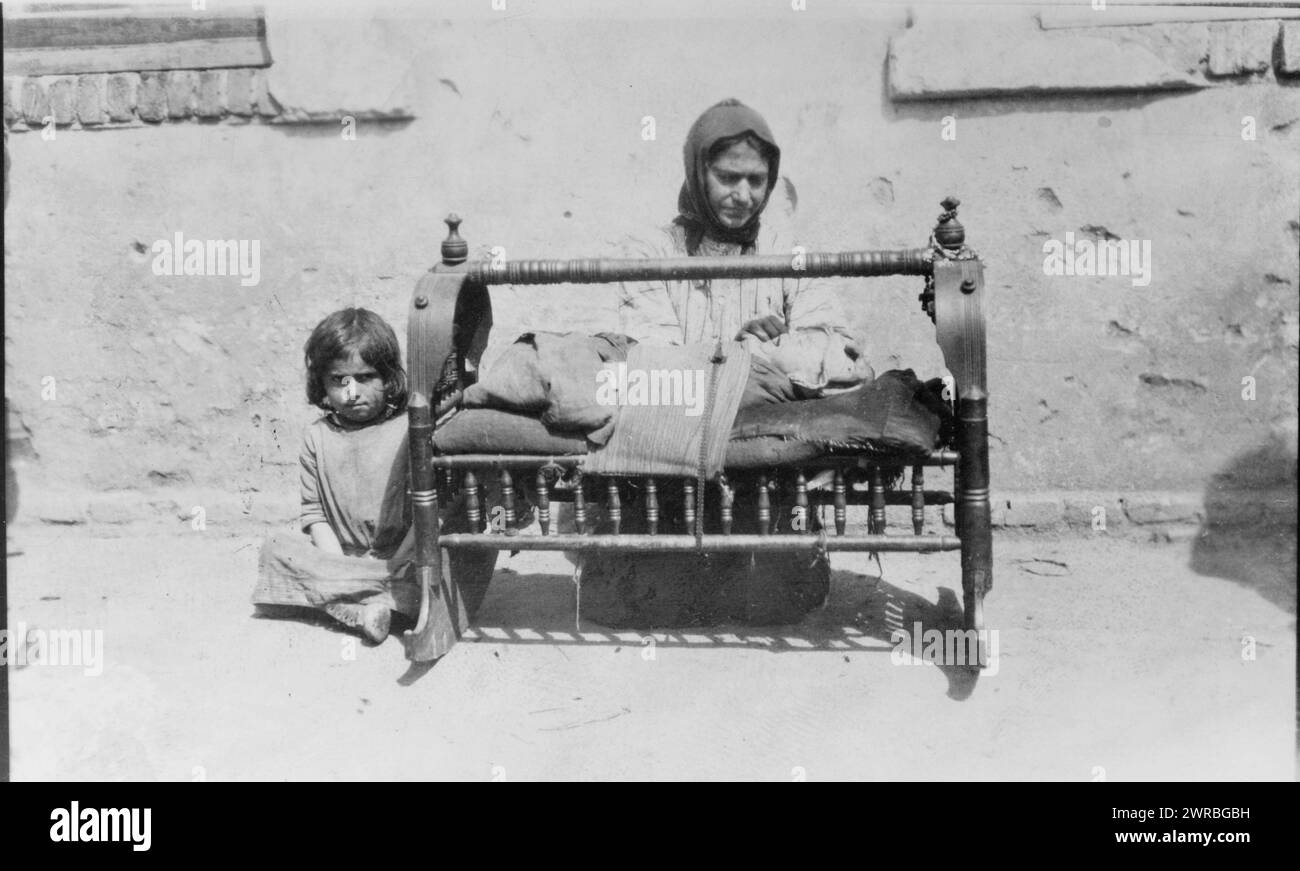 Wiegen haben keine Seiten, ein breites Stoffband, das das Baby vor dem Herausfallen schützt, armenische Frau mit Baby in der Wiege, ein weiteres Kind sitzt neben ihr., zwischen 1915 und 1923, Naher Osten, 1910-1930, Fotodrucke, 1910-1930., Fotodrucke, 1910-1930, 1 Fotodruck Stockfoto
