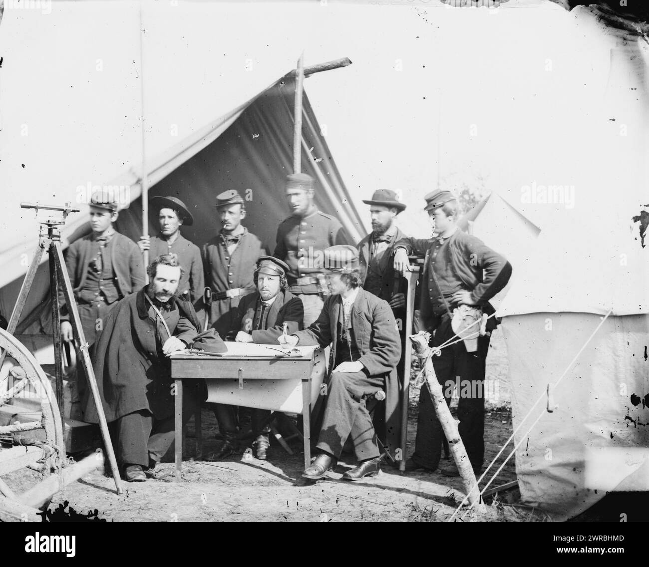 Yorktown, Virginia, Umgebung. Topographische Ingenieure, Camp Winfield Scott, Foto zeigt eine Gruppe von neun Männern, die vor einem Zelt posierten, mit einem Vermessungsinstrument links. Die beiden Männer, die in der Mitte und rechts sitzen, sind wahrscheinlich Frederick W. Door und John W. Donn. Der Offizier auf der linken Seite ist William H. Paine, der die Stahlbandrolle erfand, die der Mann auf der rechten Seite trug. An zweiter Stelle von rechts scheint Allan Pinkerton zu stehen. Foto vom östlichen Kriegsschauplatz, The Peninsular Campaign, Mai-August 1862. Gibson, James F., 1828, Fotograf, 2. Mai 1862. Stockfoto