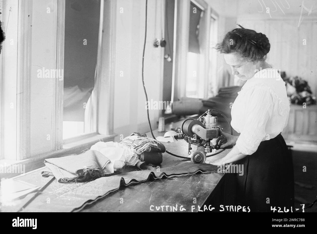 Das Foto zeigt eine Frau, die Streifen für amerikanische Flaggen mit Maschinen auf der Brooklyn Navy Yard, Brooklyn, New York, 1917. Juli, 7. 1 negativ: Glas Stockfoto