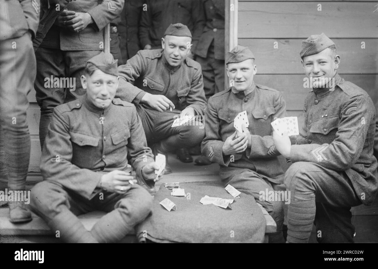 Karten, Foto zeigt eine Gruppe von Soldaten, die während eines Kartenspiels spielen. Schulterpflaster identifizieren sie als Mitglieder der 42. Infanteriedivision, der Regenbogendivision, zwischen ca. 1915 und ca. 1920, Glasnegative, 1 negativ: Glas Stockfoto