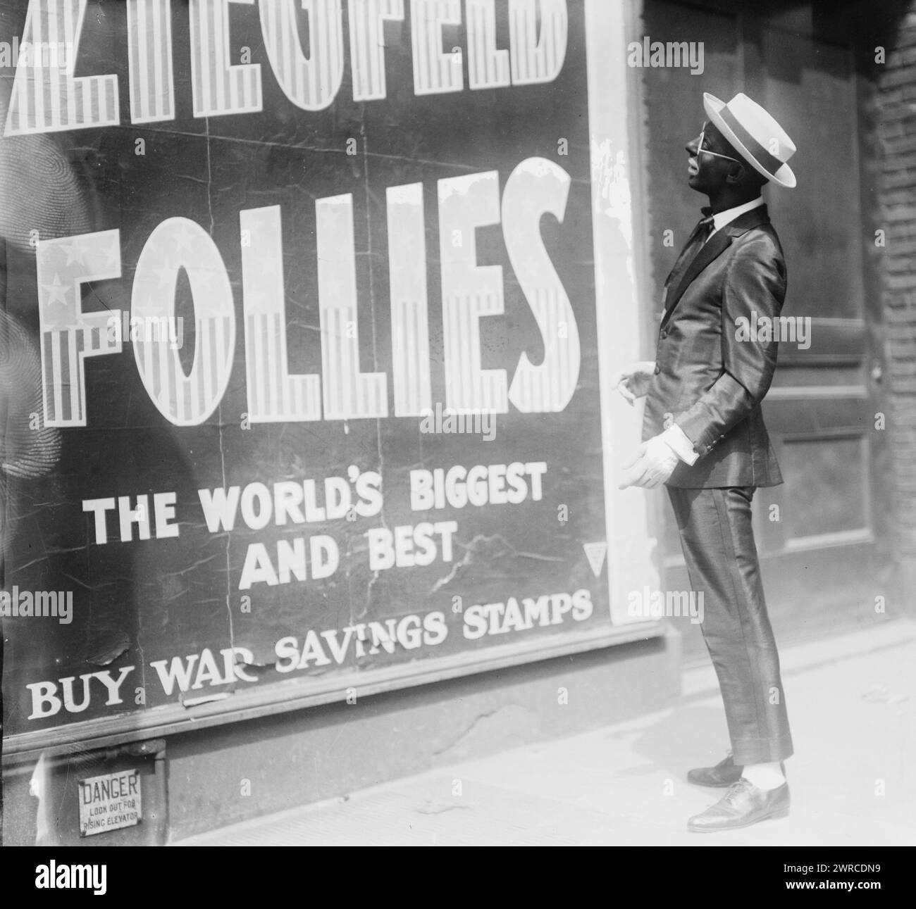 Cantor, Foto zeigt Sänger Eddie Cantor (1892–1964) in schwarzem Gesicht vor einer Werbetafel für die Ziegfield Follies mit 'Buy war Saving Stamps'-Aussage., zwischen 1917 und ca. 1920, Glasnegative, 1 negativ: Glas Stockfoto