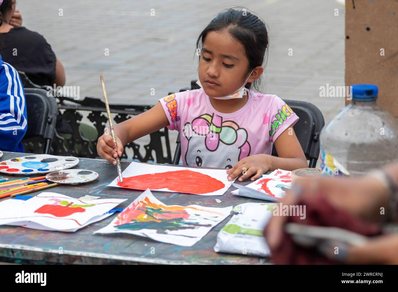 Oaxaca, Mexiko - Studenten, die in einem temporären Kunstkurs im Zocalo malen. Ein Mädchen malt ein Herz am Tag vor Valentinstag. Stockfoto