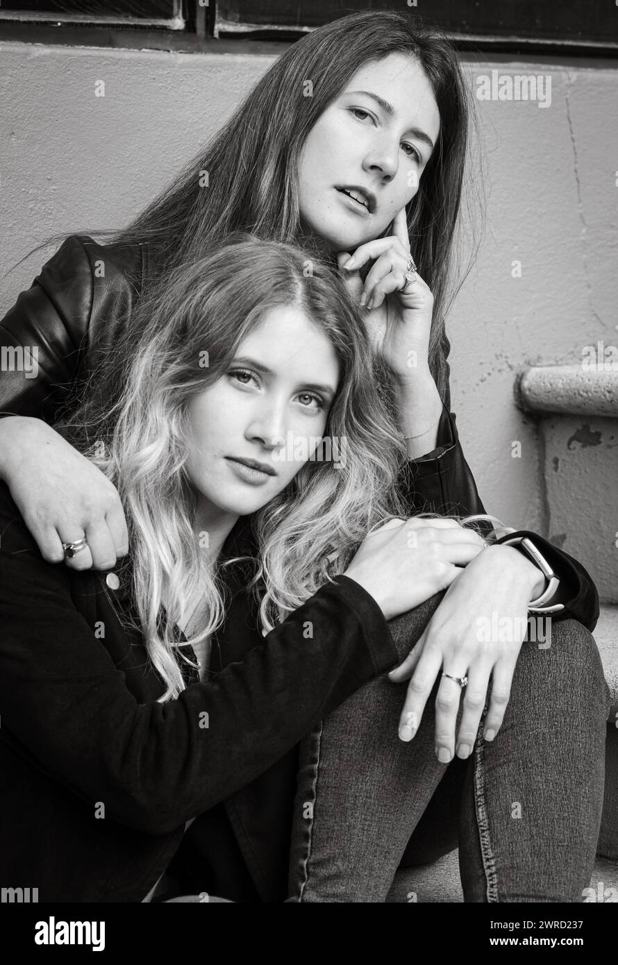 Zwei Freundinnen sitzen in Graustufen auf städtischen Treppen Stockfoto