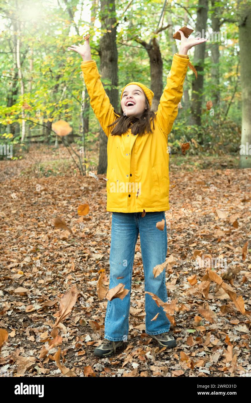 Der Herbst ist eine Jahreszeit der Freude. Ein Teenager wirft sich im November in einem Park Herbstlaub über den Kopf Stockfoto