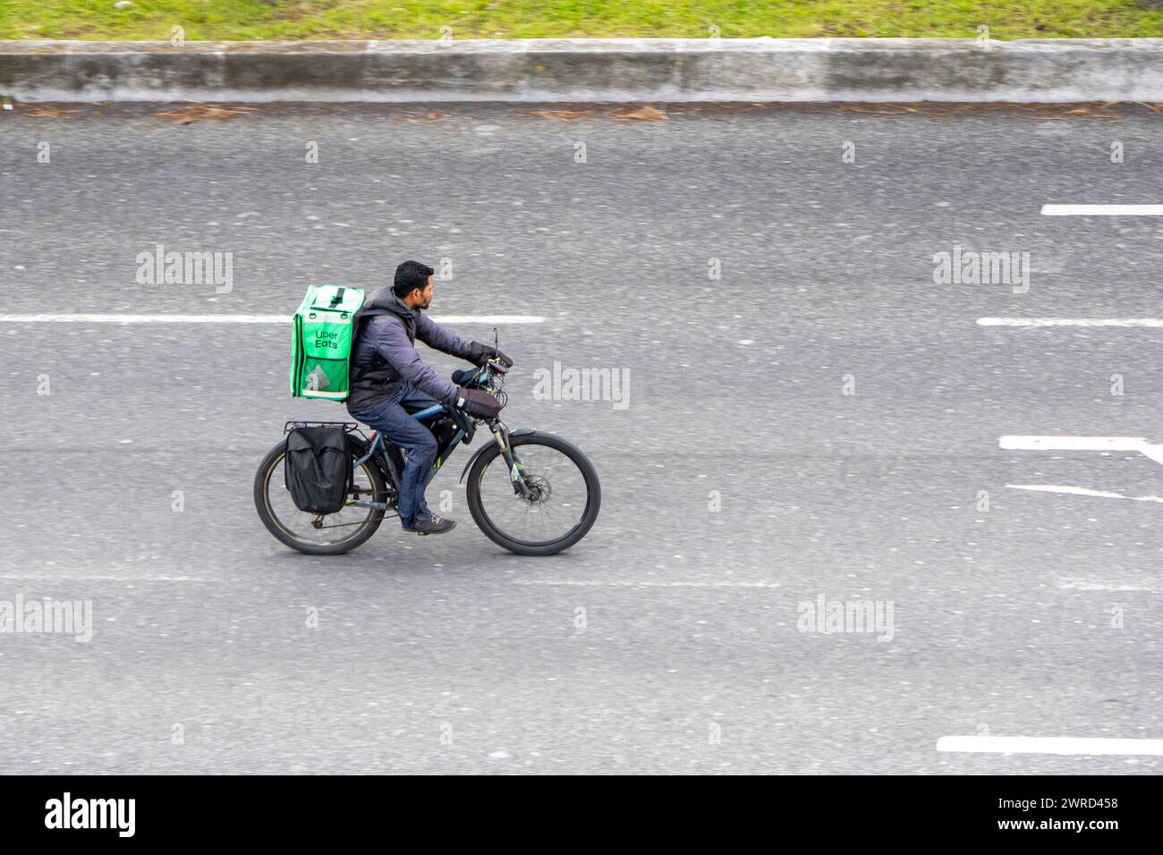 Lissabon, Portugal am 11. März 2024 reist der Mitarbeiter von Uber Eats in Lissabon mit einem Elektrofahrrad ohne Schutz oder Lichtsignalisierung auf der Straße Stockfoto