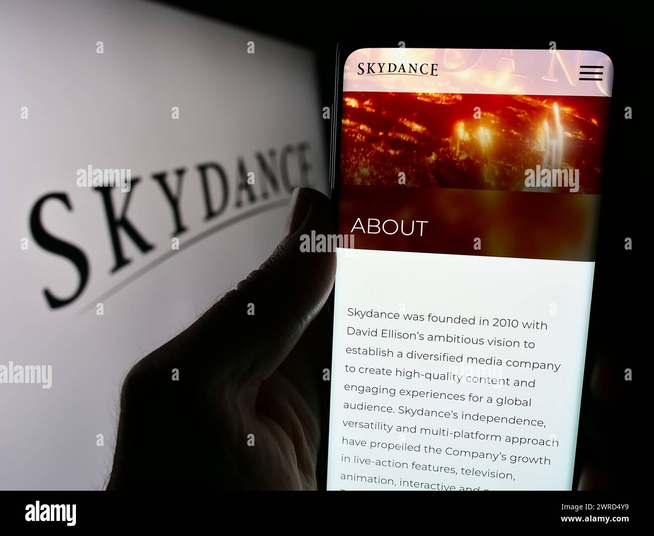 Person mit Handy und Website der US-amerikanischen Filmproduktionsfirma Skydance Media LLC vor dem Logo. Konzentrieren Sie sich auf die Mitte des Telefondisplays. Stockfoto