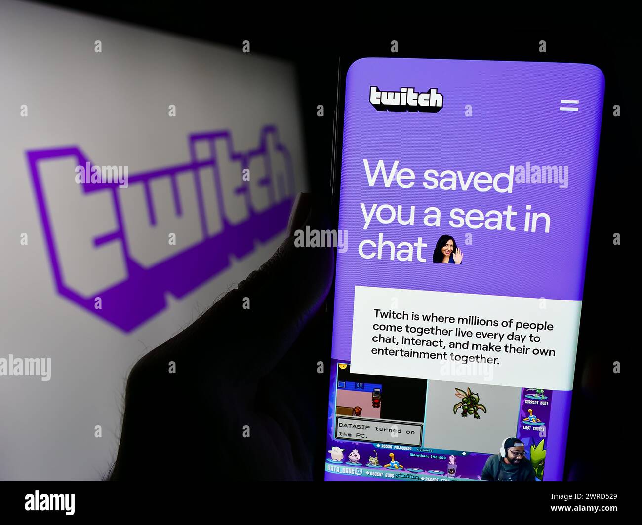 Person mit Smartphone und Webseite des US-amerikanischen Live-Streaming-Unternehmens Twitch Interactive Inc. Vor dem Logo. Konzentrieren Sie sich auf die Mitte des Telefondisplays. Stockfoto