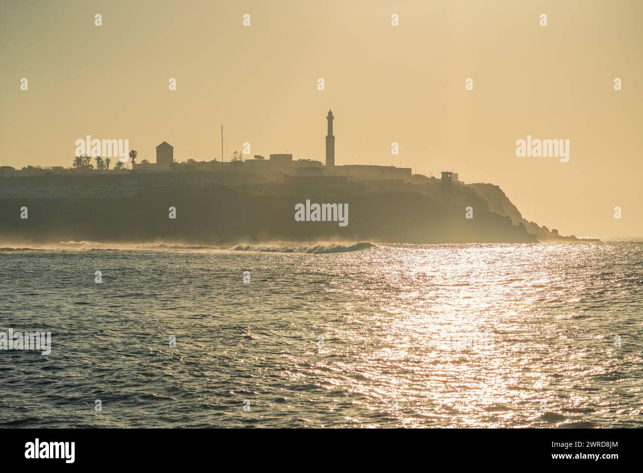 Malerischer Blick auf die marokkanische Küste bei Sonnenuntergang mit einer Stadt mit Leuchtturm Stockfoto