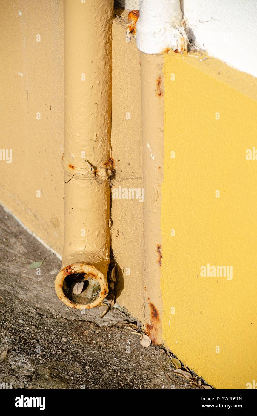 Detail eines alten Eisenrohrs an einer gelb bemalten Wand Stockfoto