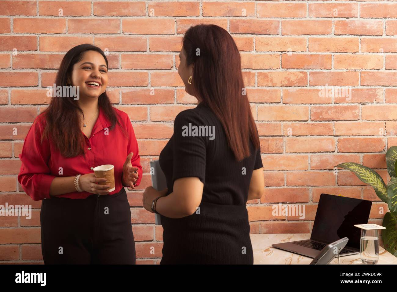 Zwei Geschäftsfrauen unterhalten sich während der Kaffeepause im Büro Stockfoto