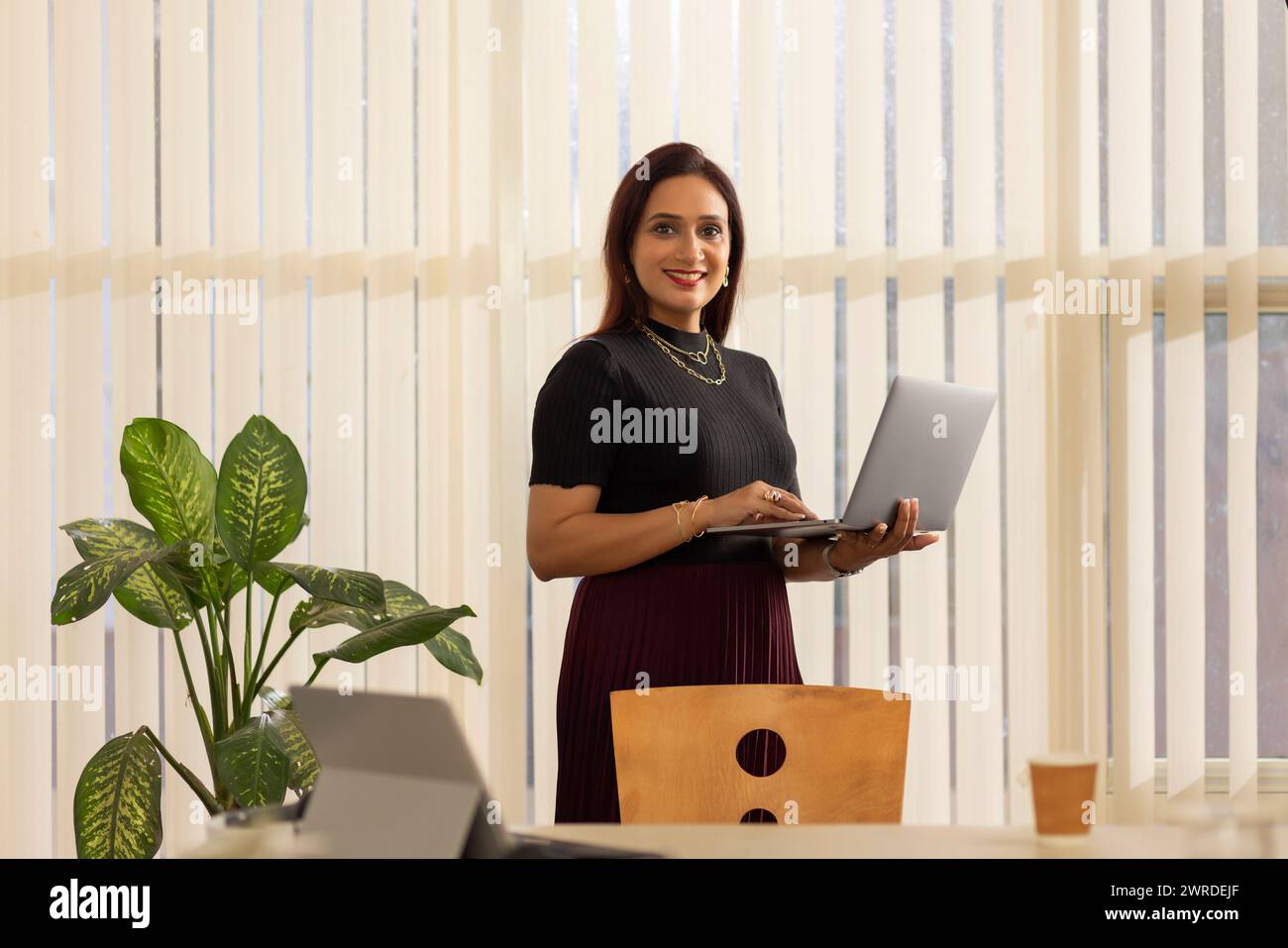 Lächelnde Unternehmerin mit Laptop im Büro Stockfoto