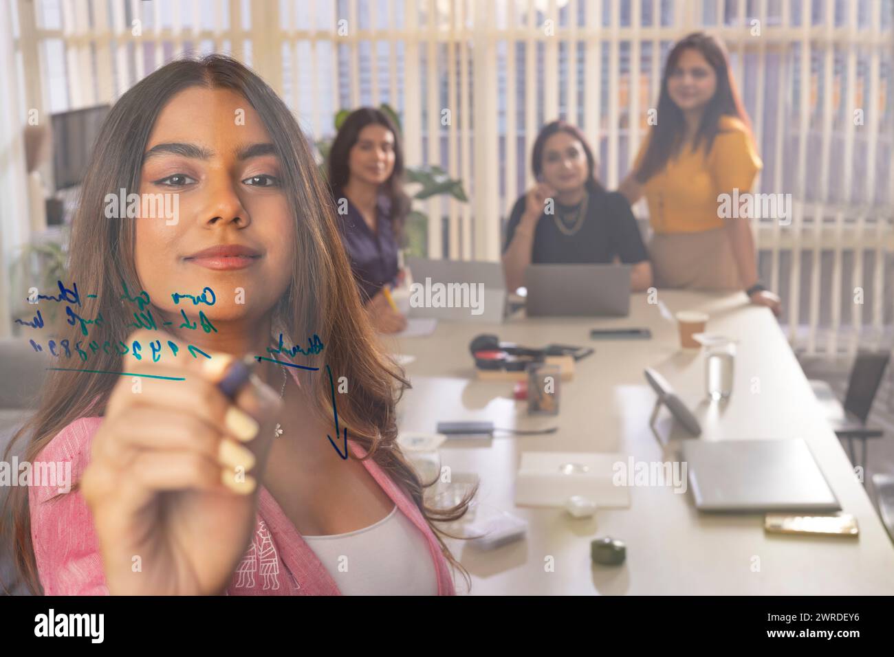 Geschäftsfrau, die auf Glas schreibt, während sie im Konferenzraum eine Geschäftspräsentation hält Stockfoto