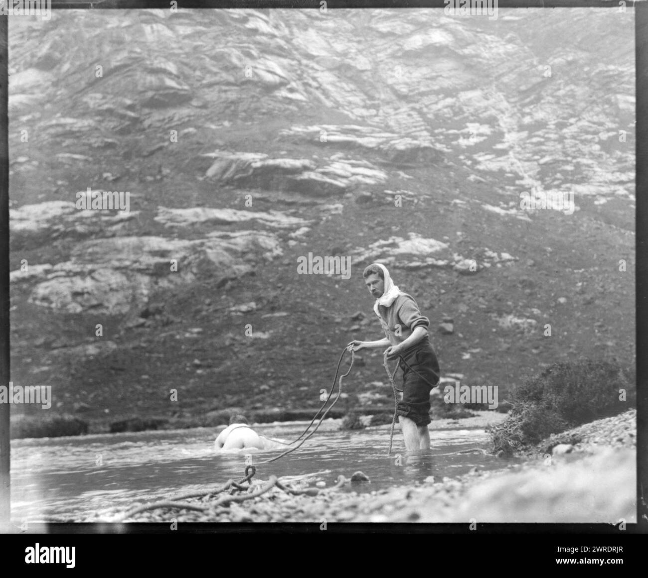 Person, die über den Fluss kriecht, gesichert von einem Mann, der eine Seiltour hält, um 1900, möglicherweise Cuillin Mountains, Skye, Schottland, Großbritannien Stockfoto