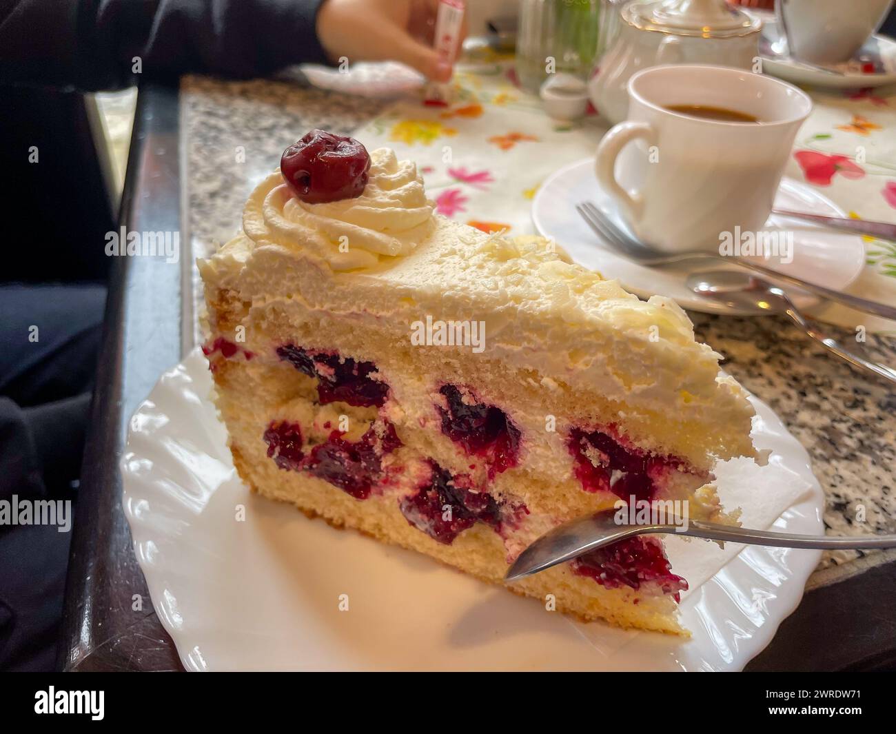 Ein Stück Kuchen mit Beeren und einer Tasse Kaffee Stockfoto