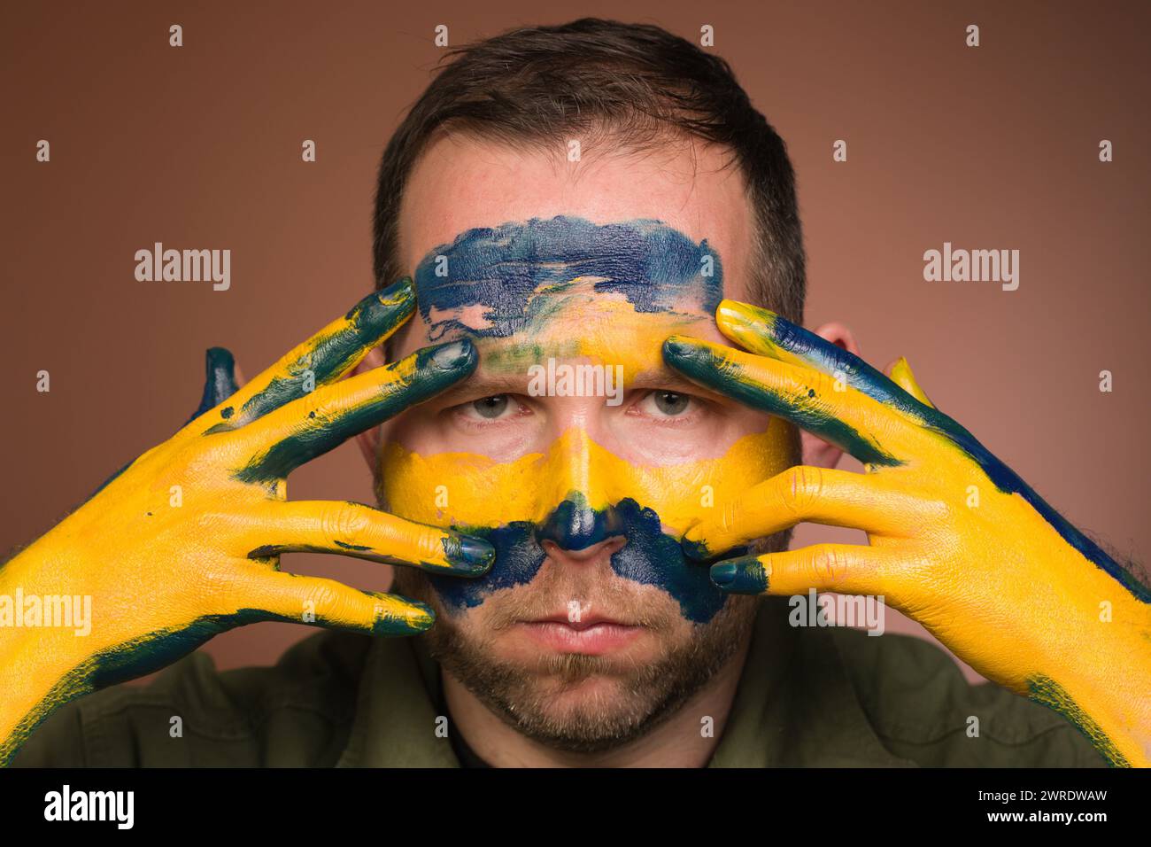 Mann, der Respekt vor der Ukraine mit nationalen Farben im Gesicht ausdrückt Stockfoto