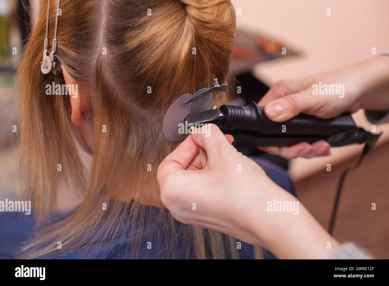 Der Friseur hat Hair Extensions zu einem jungen Mädchen, eine Blondine in einem Schönheitssalon. Professionelle Haarpflege. Stockfoto