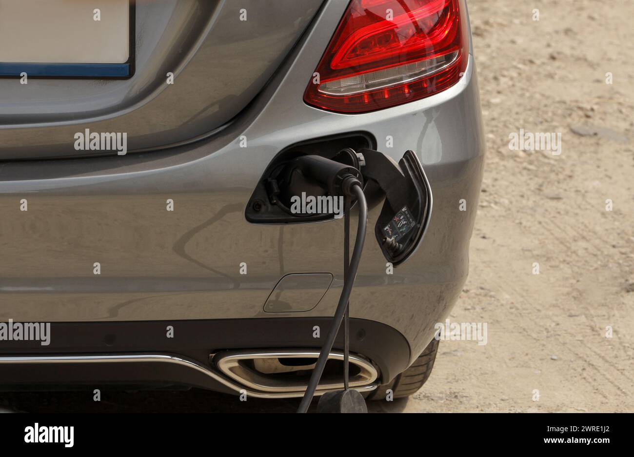 Ein graues Auto wird mit einem tragbaren Kabel aufgeladen. Stockfoto