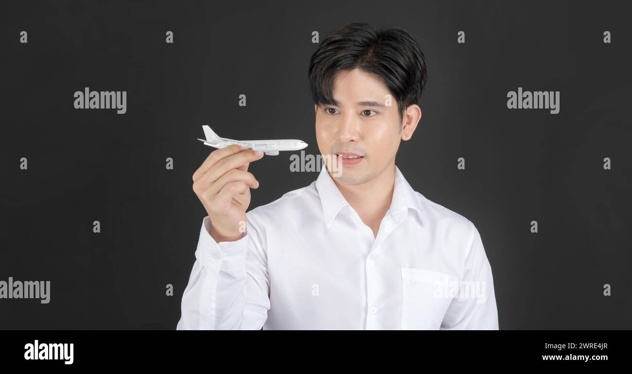Geschäftsmann hält ein sauberes, weißes Spielzeugflugzeug, das bedeutet, dass man auf dunklem Hintergrund fliegen kann Stockfoto