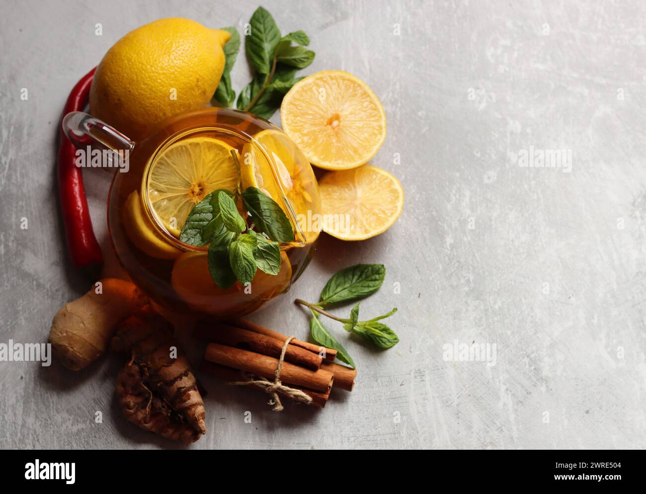 Stilleben mit Glas-Teekanne, Zitronen und Minzblättern auf einem Tisch. Gesundes hausgemachtes Getränk schließt Foto. Stockfoto