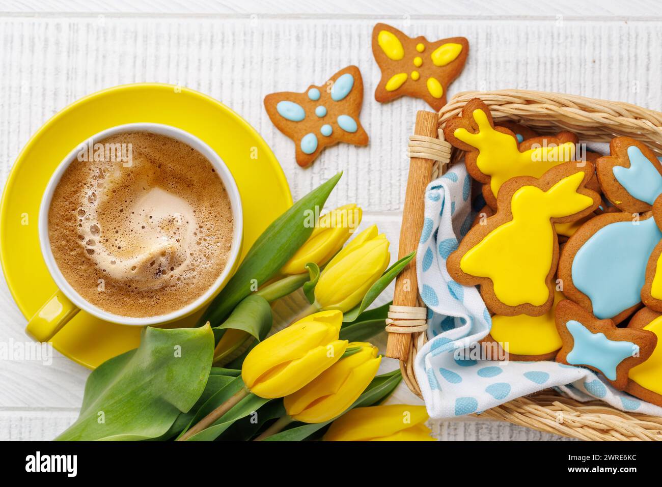 Osterszene mit hasenförmigen Lebkuchen-Keksen, gelben Tulpen und Kaffeetasse. Flache Lagen Stockfoto