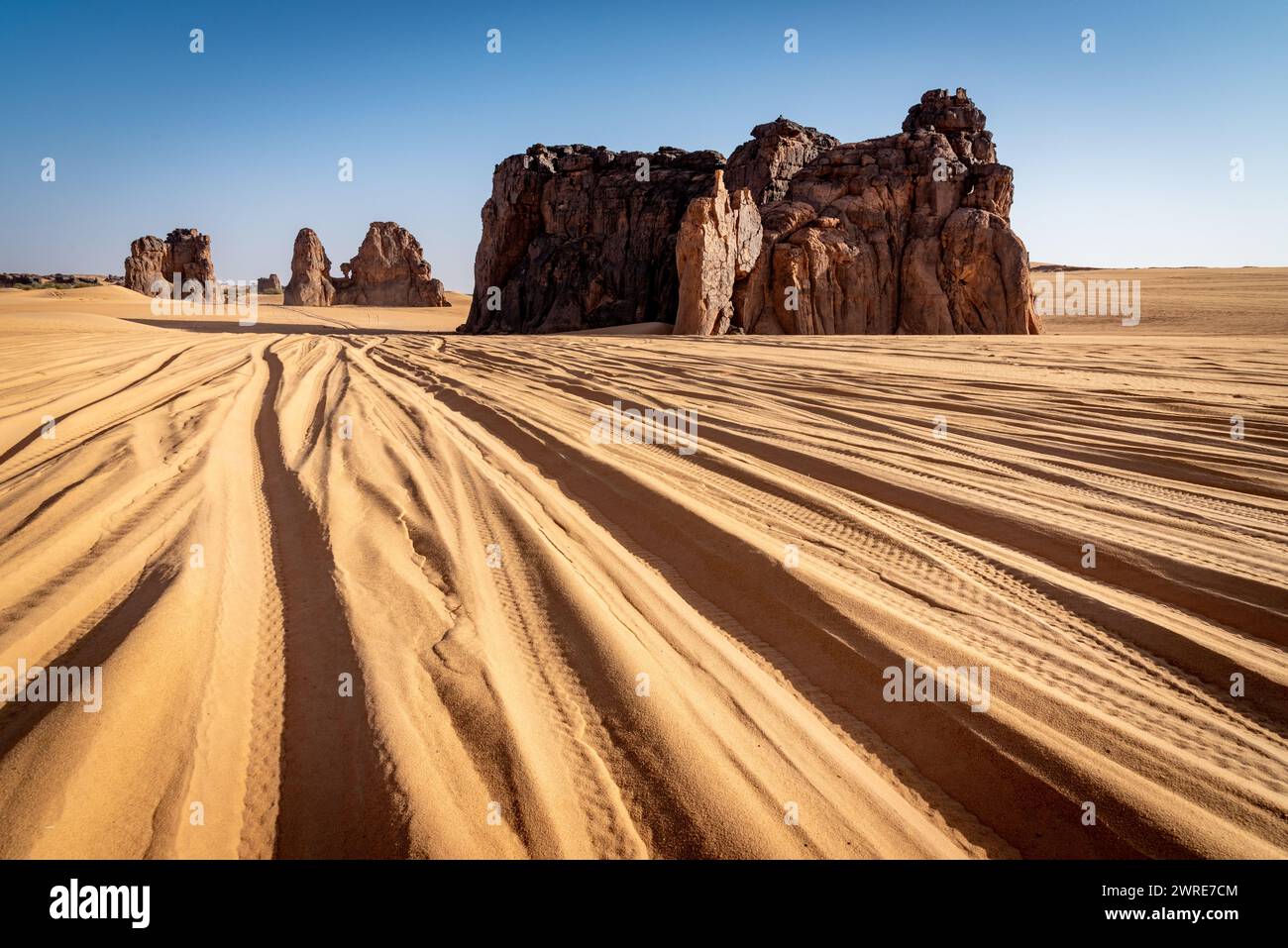 Landschaft von Erg Admer in der Sahara, Algerien. Die Spuren zahlreicher Jeeps treffen sich zu den Felsformationen des La Vache Qui Pleure Sit Stockfoto