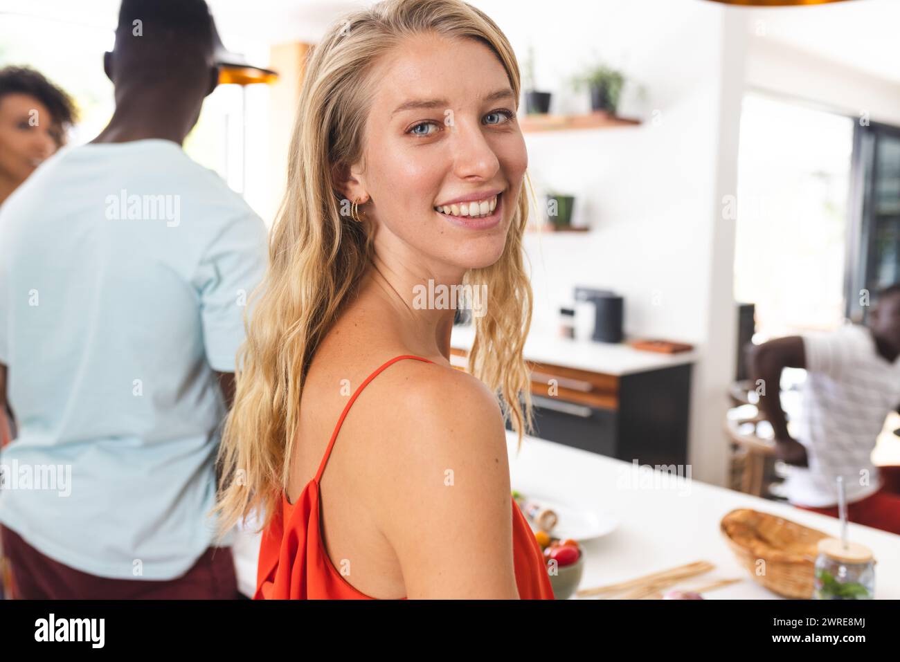 Junge kaukasische Frau in rotem Oberteil lächelt bei einer gesellschaftlichen Versammlung Stockfoto