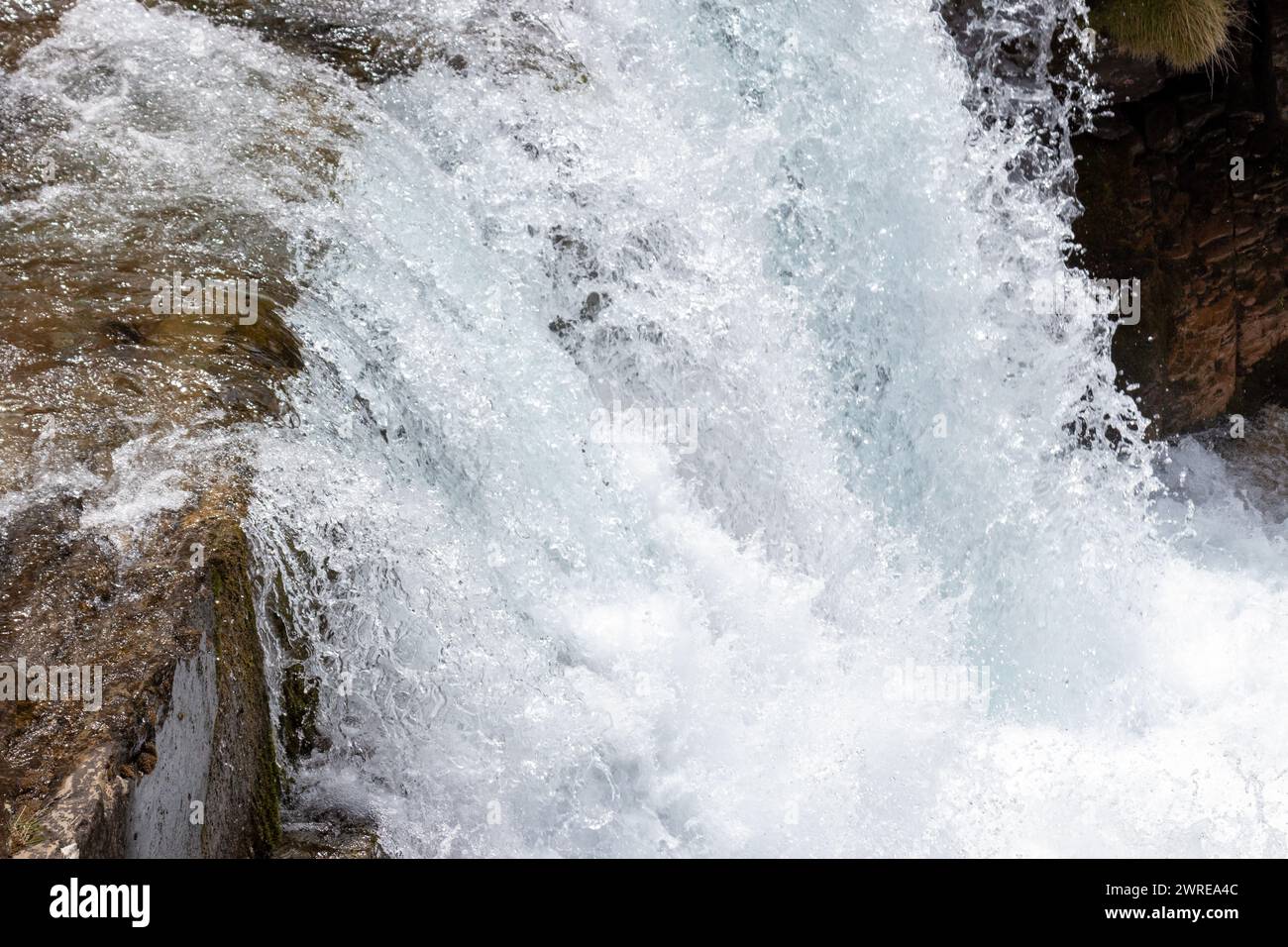 Schneller, klarer Fluss, der über glatte, moosbedeckte Felsen in einer natürlichen Umgebung fließt Stockfoto