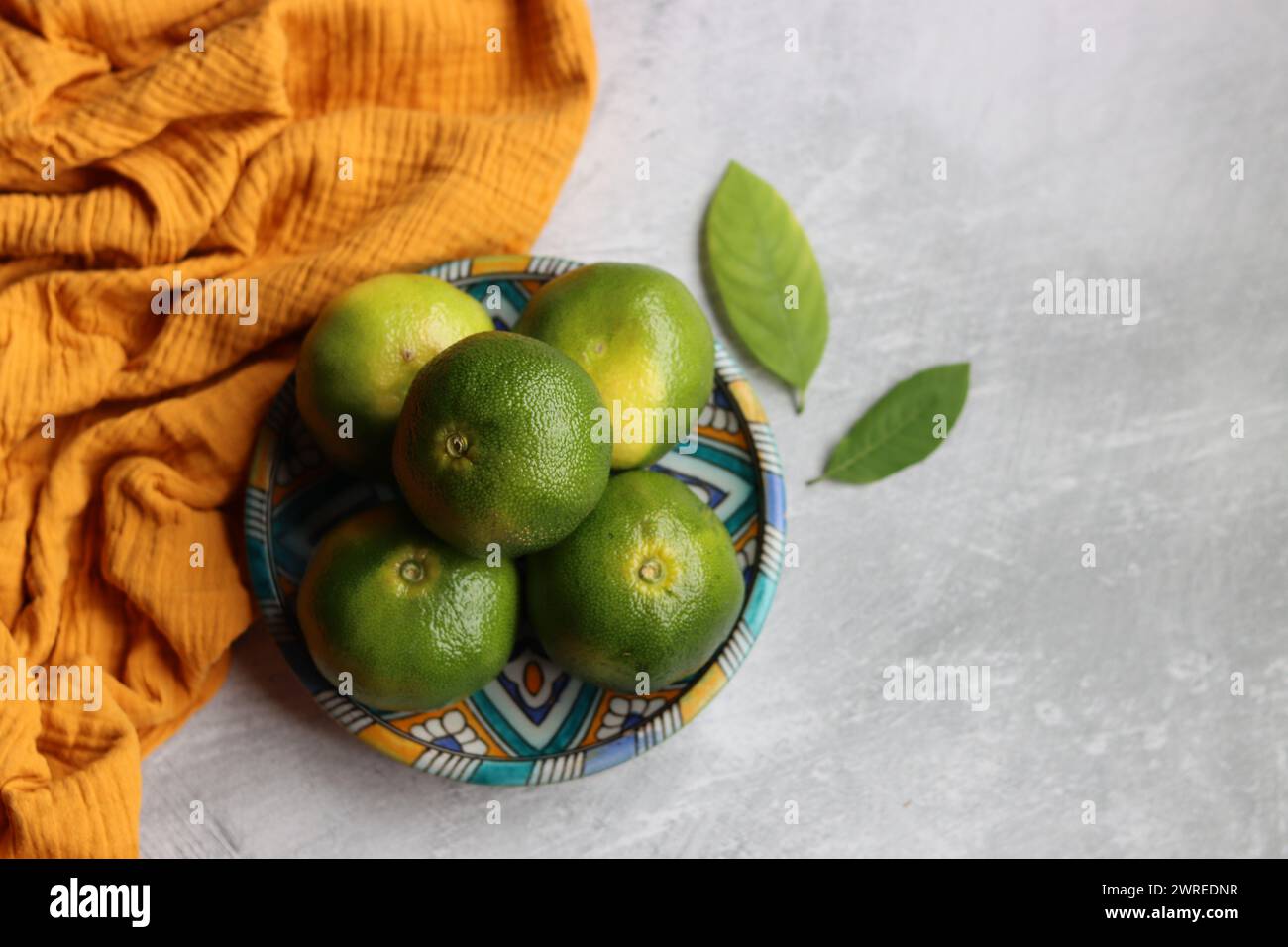 Einfache Kompositionen Stillleben mit grünen Limetten auf einer blauen Keramikplatte. Hellgrauer Hintergrund mit Platz für Text. Konzept für gesunde Ernährung. Stockfoto