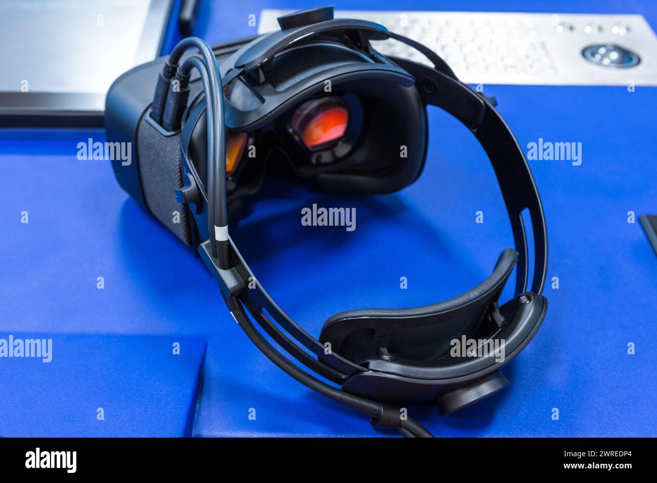 Schwarzes VR-Headset mit roten Visieren auf blauem Schreibtisch, Rückansicht, Nahaufnahme mit selektivem Fokus Stockfoto