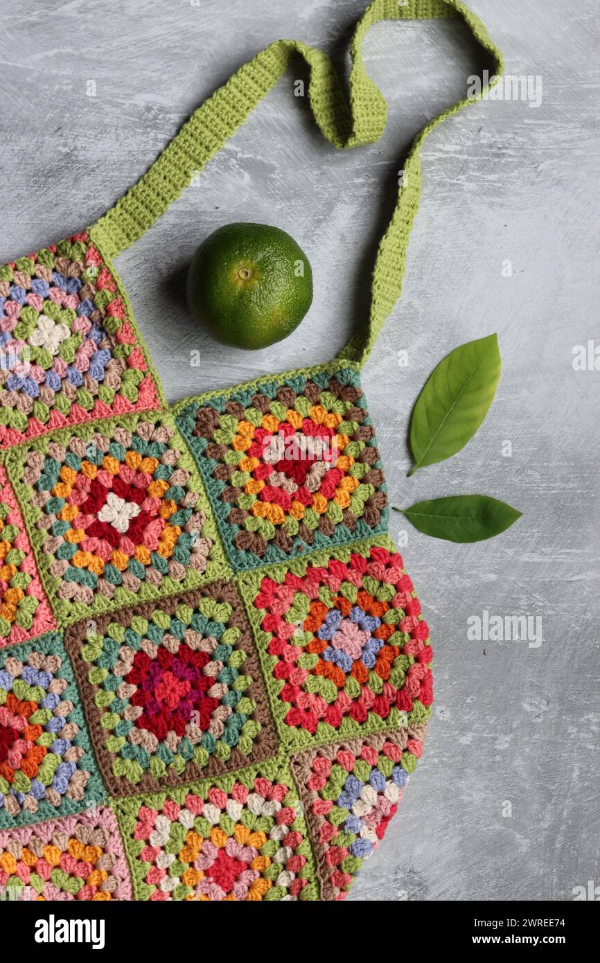 Bunte Einkaufstasche aus Bio-Baumwolle. Häkeln Sie die Textur aus der Nähe des Fotos. Umweltfreundliche Tasche. Quadratisches Granny-Muster. Stockfoto