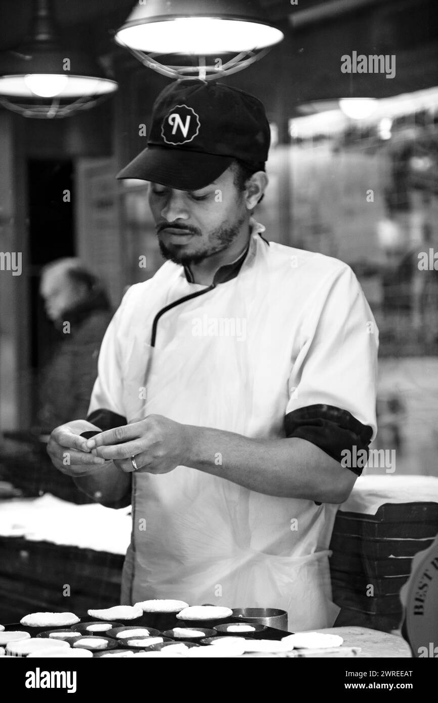 Der Küchenchef bereitet köstliche Gerichte in der belebten Restaurantküche zu und zeigt kulinarische Meisterleistungen in Aktion Stockfoto