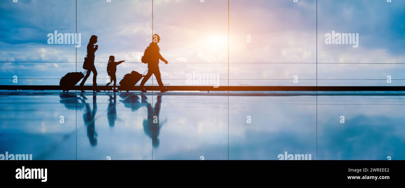 Familie am Flughafen, die mit einem kleinen Kind zum Abflugsteig reist. Familienurlaub und Urlaubskonzept mit Silhouette von Eltern und Kind. Trav Stockfoto