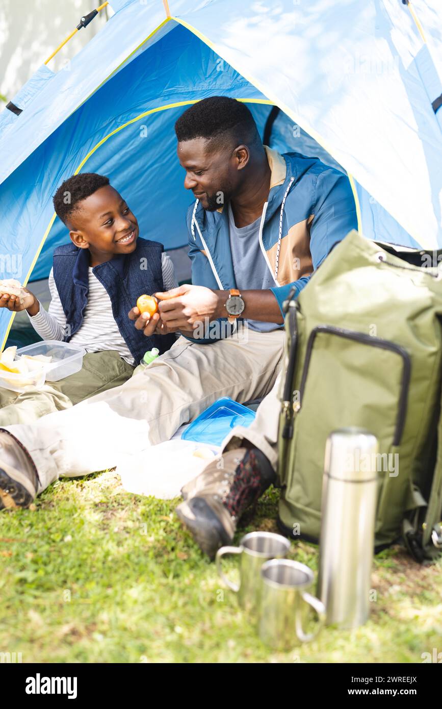 Afroamerikaner Vater und Sohn teilen sich einen Snack in einem blauen Zelt Stockfoto