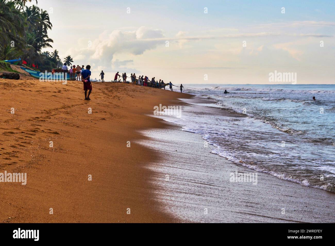 Die Leute ziehen aus dem Seefischerboot mit Fang am Strand. Waskaduwa, Sri Lanka. Stockfoto