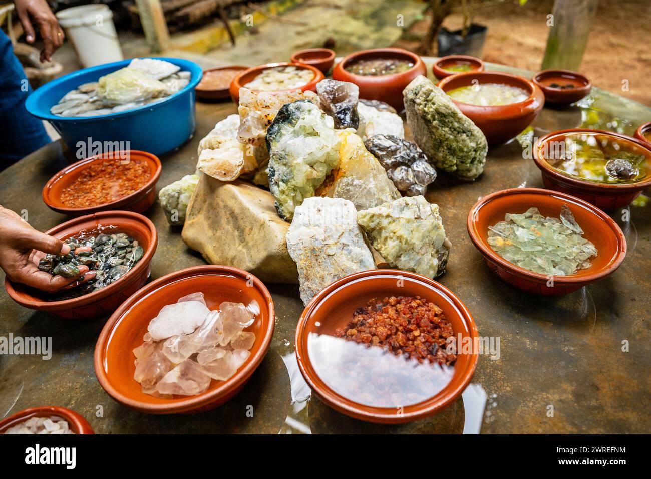 Ausstellung von abgebautem Edelstein, viele Arten und Farben in Schüssel mit Wasser auf dem Tisch. Sri Lanka. Stockfoto