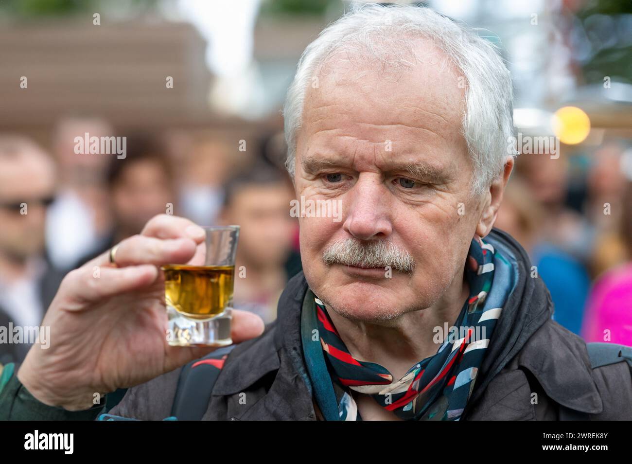 Senior Mann, der skeptisch auf ein Glas Alkohol blickt. Stockfoto