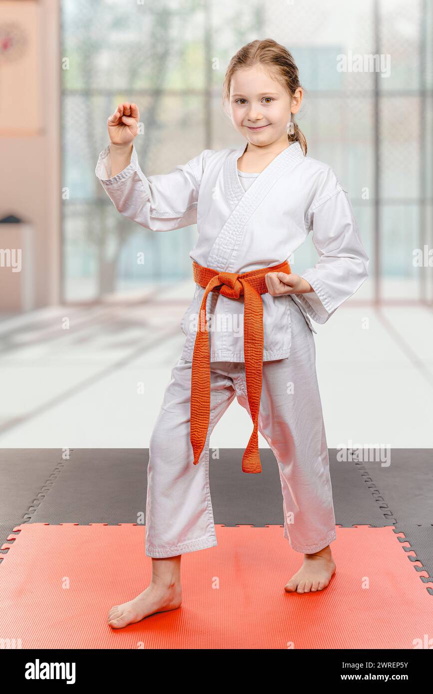 Selbstbewusstes Mädchen in Karate-Uniform posiert auf der Matte Stockfoto
