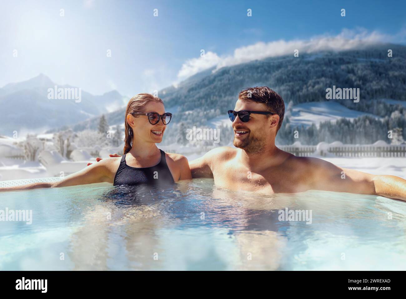 Glückliches Paar, das sich im Wannen-Whirlpool im Freien im Ski-Spa-Resort entspannt. Winterurlaub Stockfoto