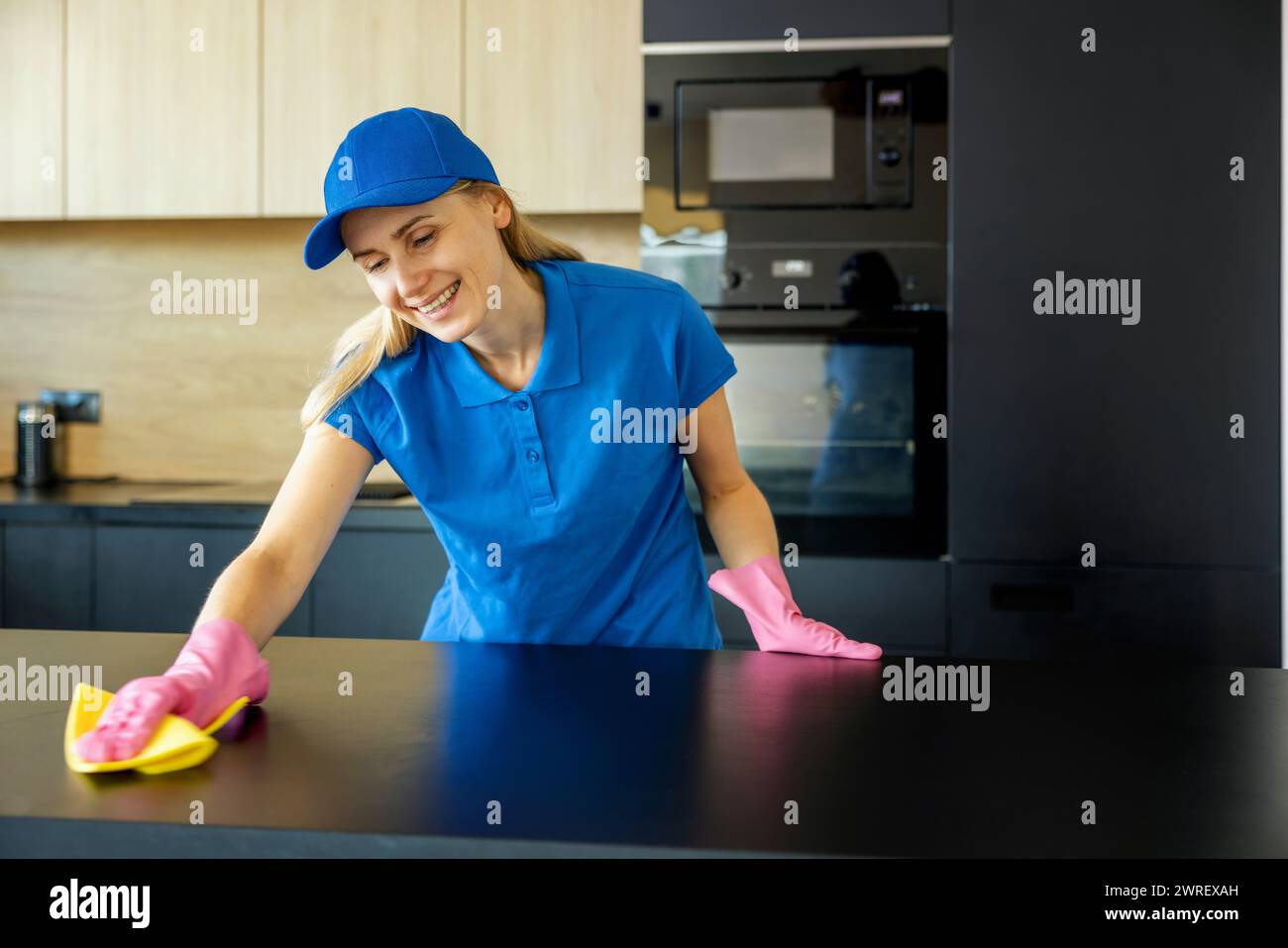 Ein lächelnder Putzservice-Mitarbeiter arbeitet in der Küche zu Hause Stockfoto