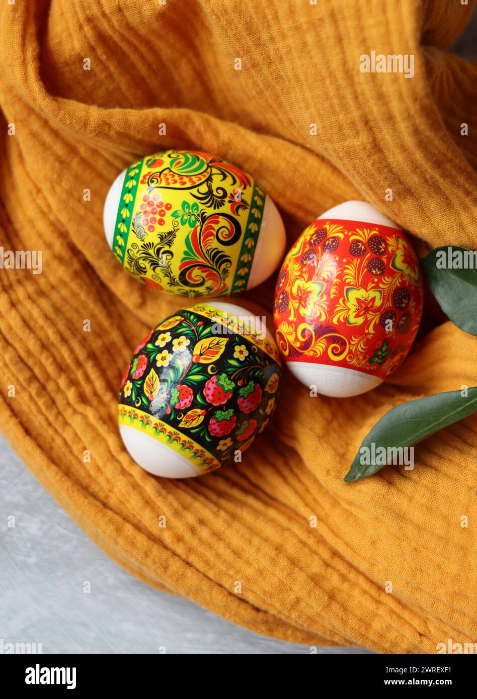 Ostereier auf einem Tisch. Stillleben mit weißen Blumen und Eiern. Foto von oben mit bunten Eiern auf einem Tisch. Osterferien Konzept. Stockfoto