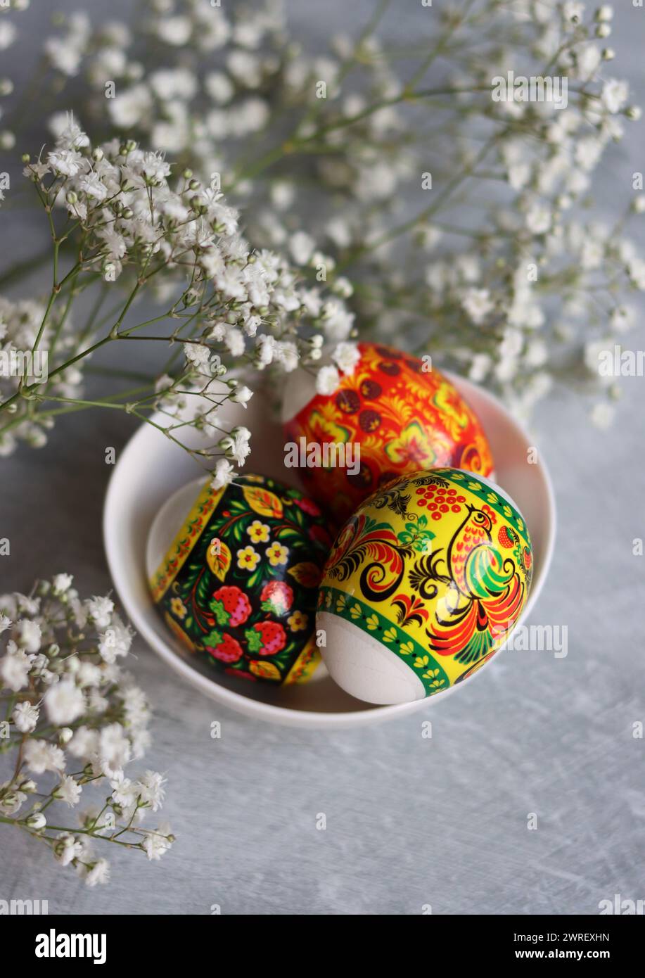 Ostereier auf einem Tisch. Stillleben mit weißen Blumen und Eiern. Foto von oben mit bunten Eiern auf einem Tisch. Osterferien Konzept. Stockfoto
