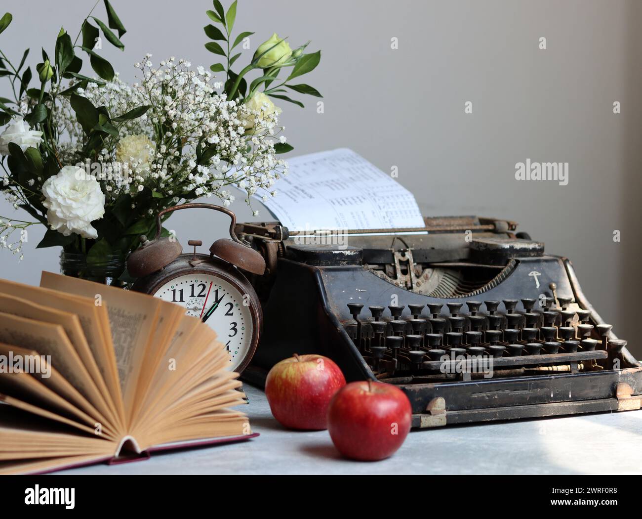 Stillleben im Retro-Stil mit offenem Buch auf dem Schreibtisch. Nahaufnahme von Vintage-Objekten. Stockfoto