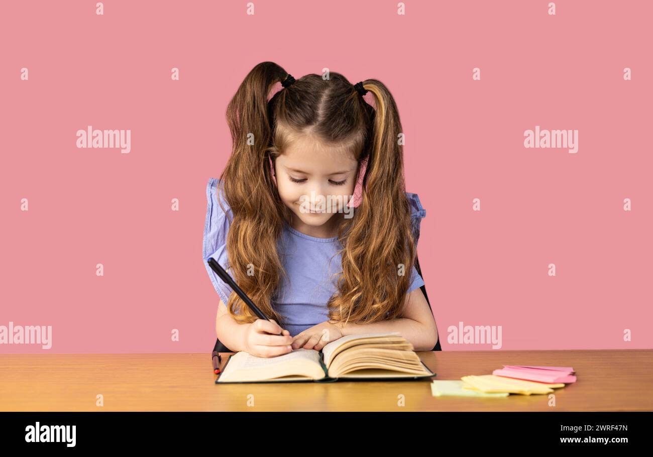 Ein kleines Mädchen macht ihre Hausaufgaben und sieht im Bild Übungen, das kleine Mädchen ist sehr aufgeregt und macht ihre Hausaufgaben mit großer Freude. Hoch Stockfoto