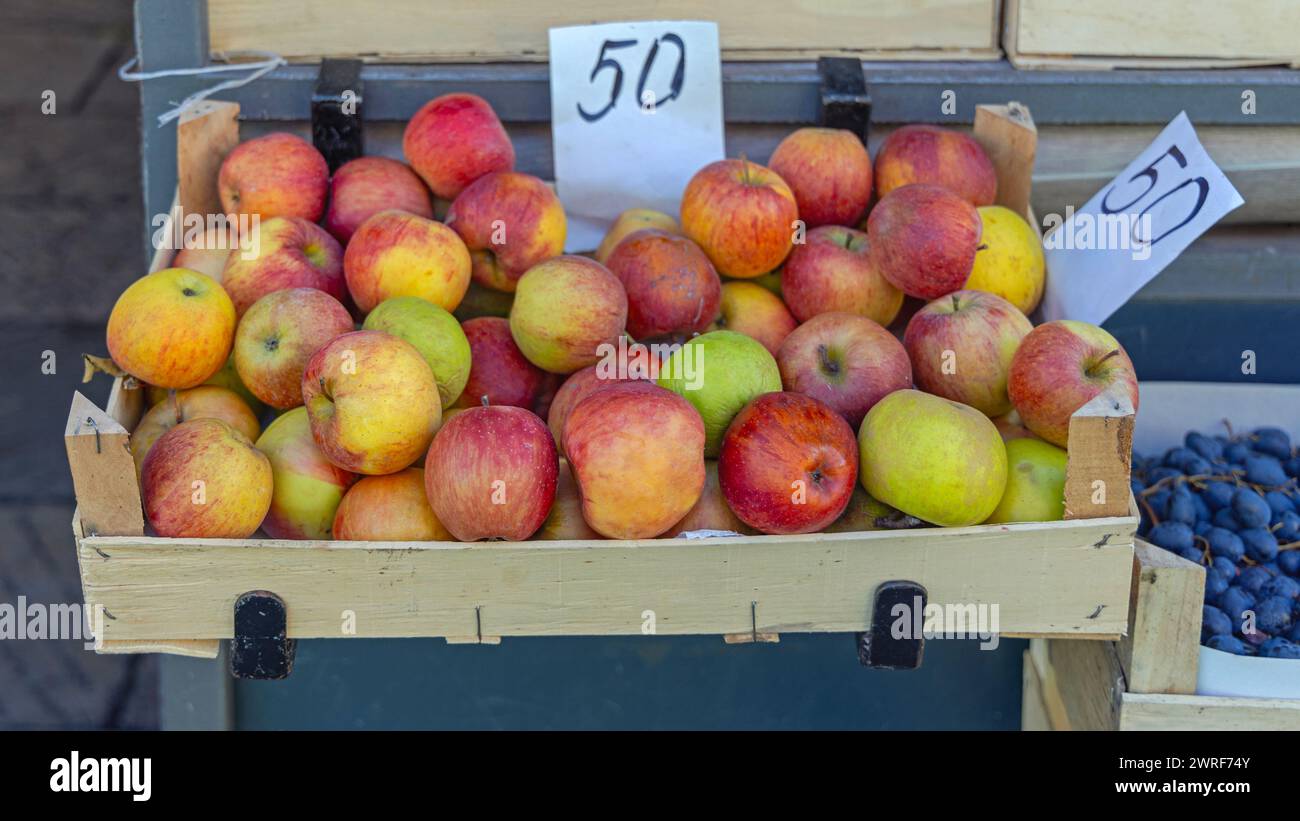 Rote Bio-Äpfel in Holzkiste mit Preisschild auf dem Bauernmarkt Stockfoto