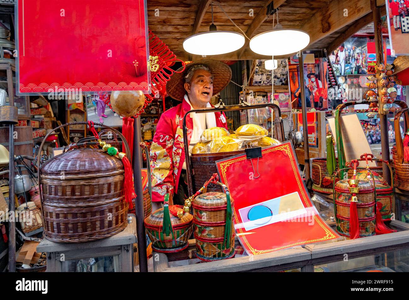 Jeden Samstag eröffnete ein Händler in traditioneller chinesischer Tracht im chinesischen Dorf Chakngeaw sein Geschäft, um gedämpfte Brötchen, Gadgets und Antiquitäten zu verkaufen. Stockfoto