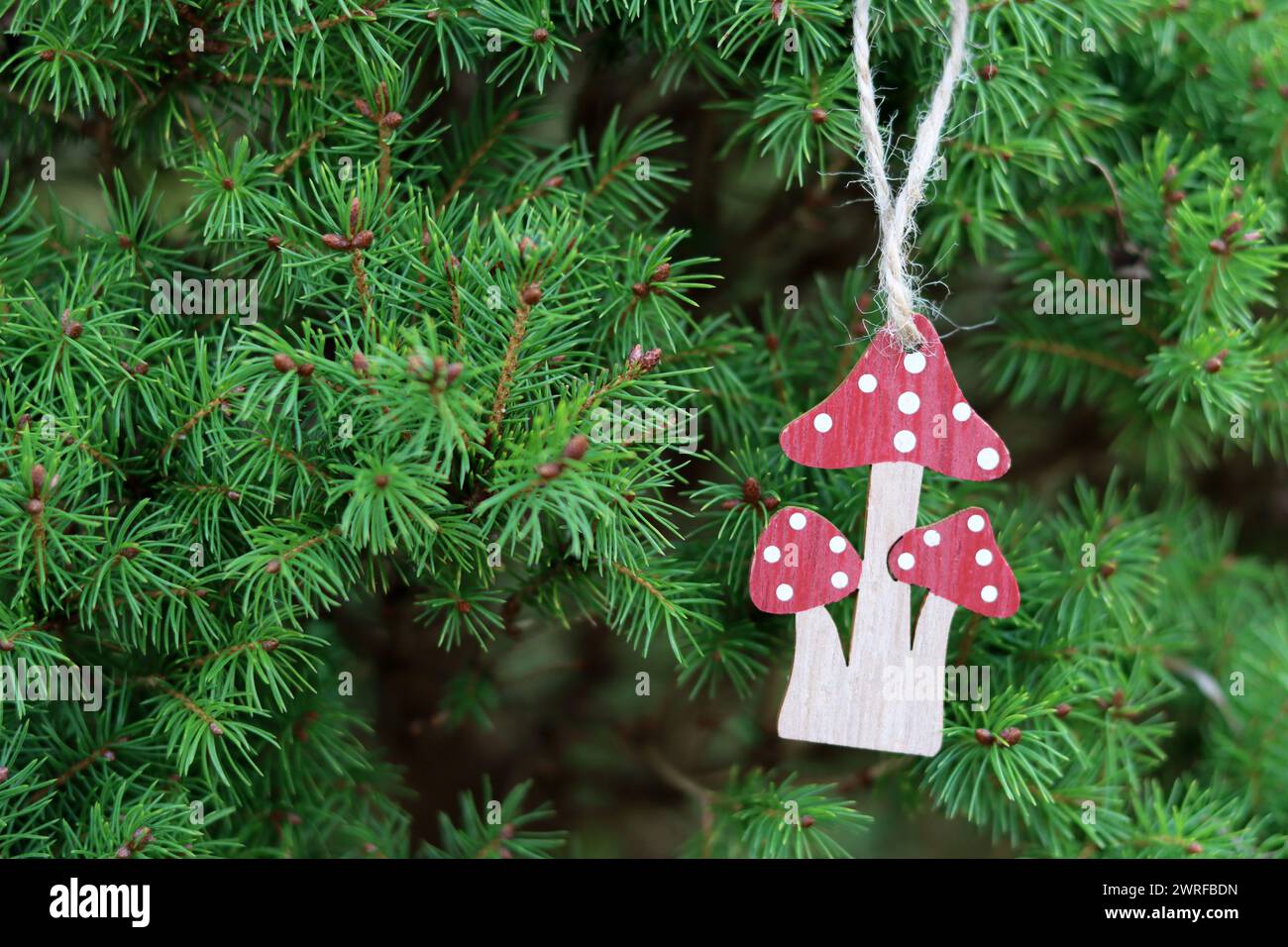 Holzspielzeugpilze auf den Zweigen eines Weihnachtsbaums. Handgemachte umweltfreundliche Urlaubsdekoration. Stockfoto